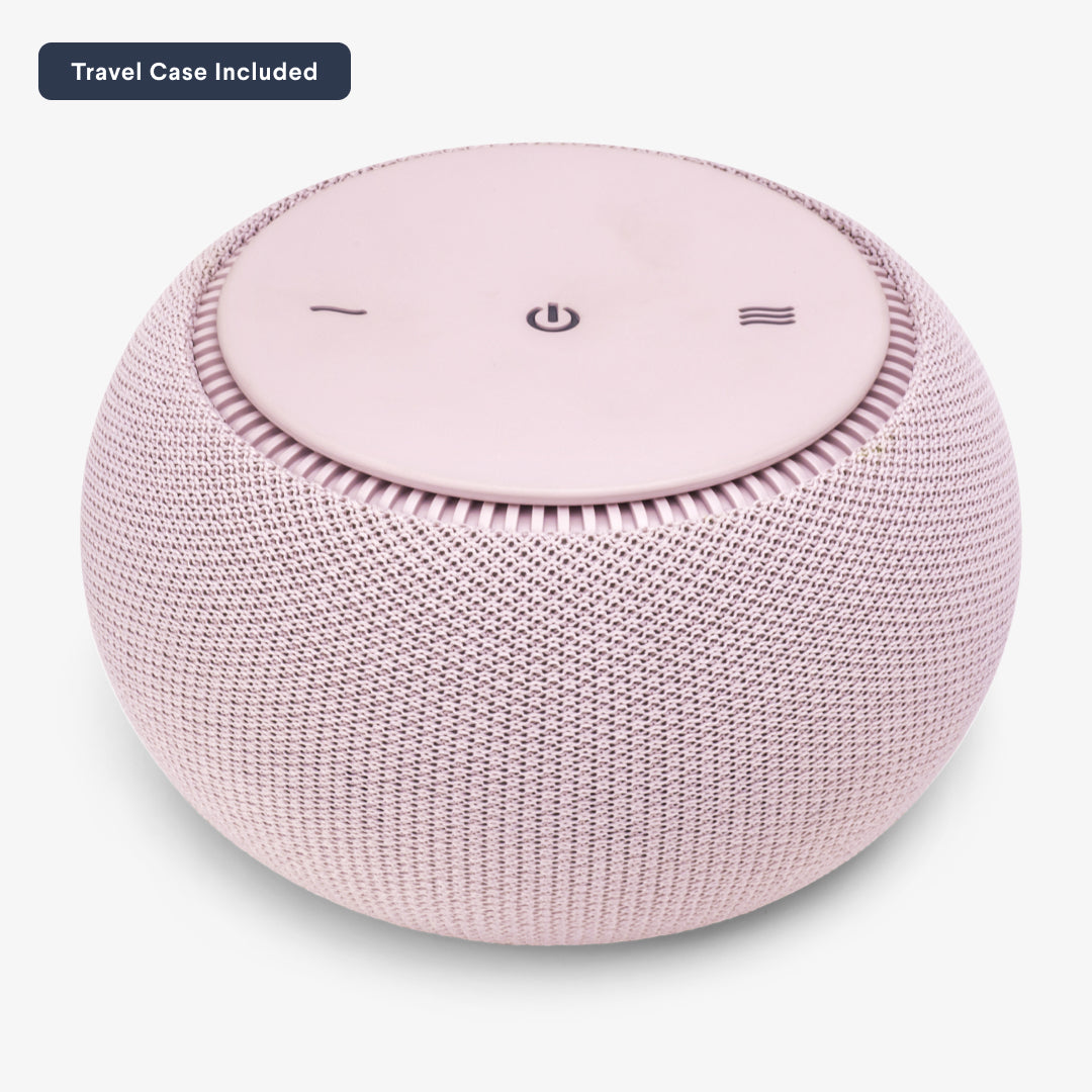 Round pink wireless speaker with control buttons on top.